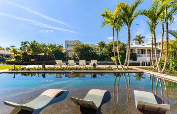 A backyard swimming pool with a hot tub and a paver patio.