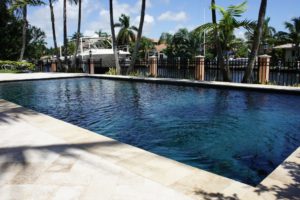 Pool cleaning and maintenance equipment on the edge of a swimming pool deck.