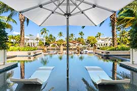 sunbeds and sun umbrella installed in a pool with a view of a bay