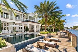 a swimming pool with a wooden deck in front of a residential house