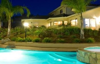 night view of a residential house with lit outdoor swimming pool