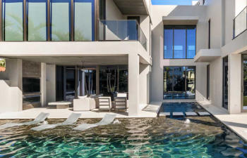 A backyard swimming pool with a hot tub and a paver patio.