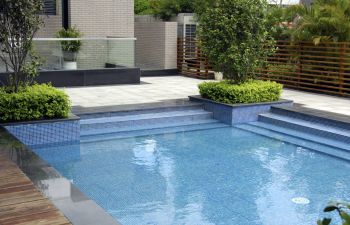 Pool cleaning and maintenance equipment on the edge of a swimming pool deck.