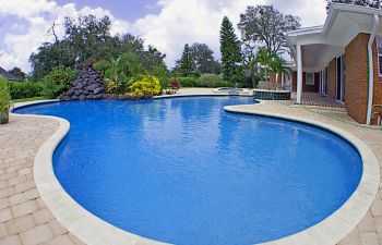 Pool cleaning and maintenance equipment on the edge of a swimming pool deck.