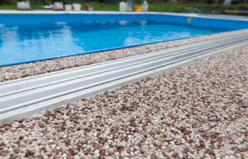 Pool cleaning and maintenance equipment on the edge of a swimming pool deck.