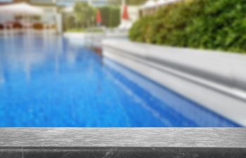 Pool cleaning and maintenance equipment on the edge of a swimming pool deck.